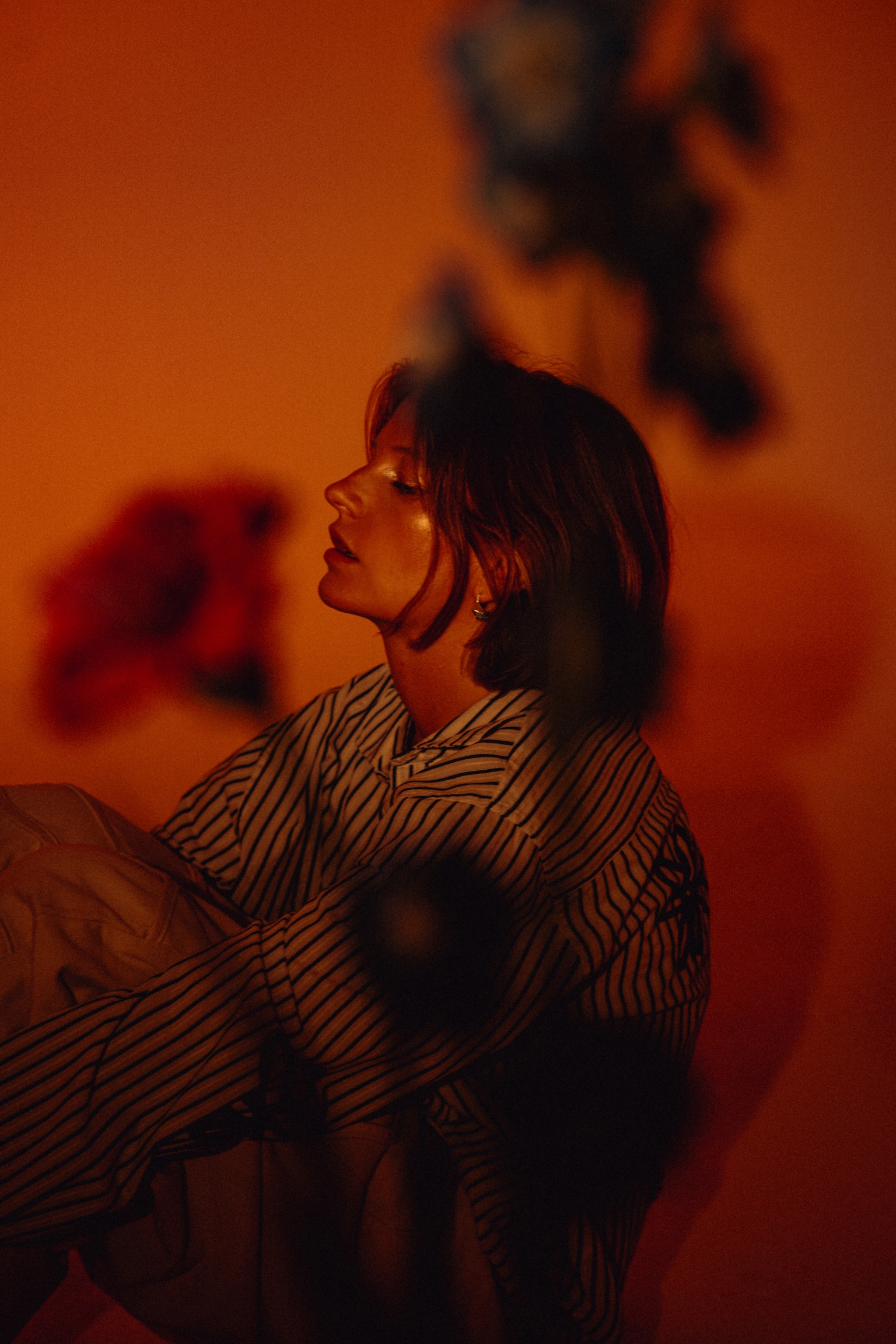 Wilhelmine sitzt im orangefarbenen Licht vor Blumen